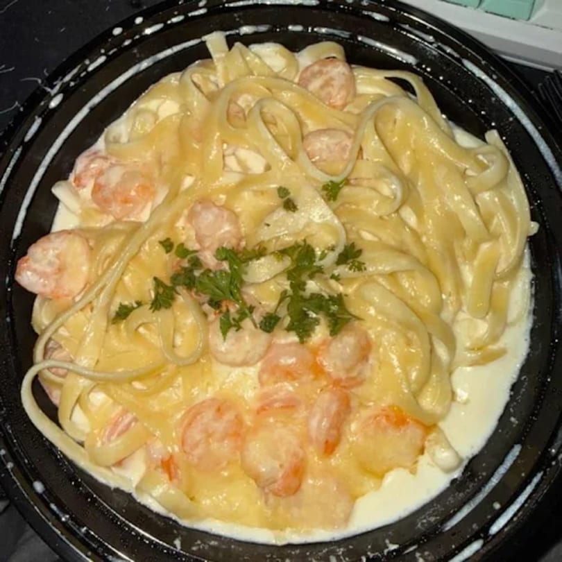 Evangelo's creamy fettuccine alfredo with shrimp and parsley in a black bowl.