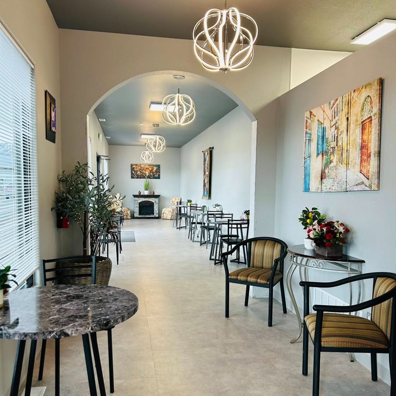 Long, narrow dining room at Evangelo's with small tables, modern lighting, and Italian-themed art.