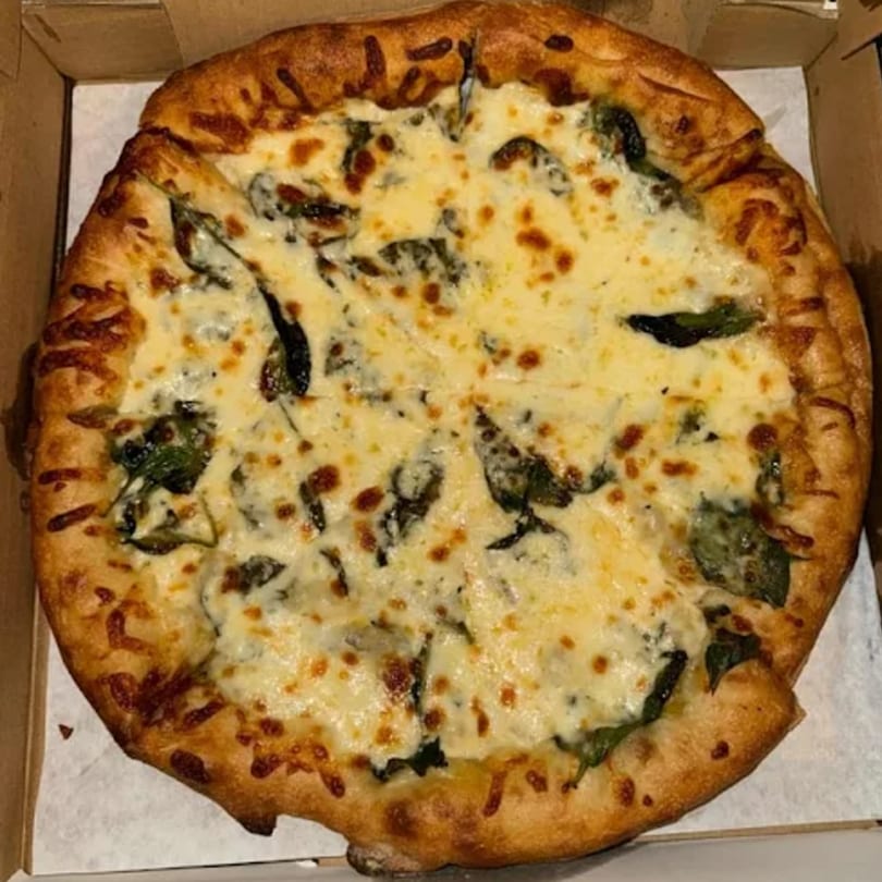 Evangelo's Italian white pizza with spinach and melted cheese in a cardboard box.