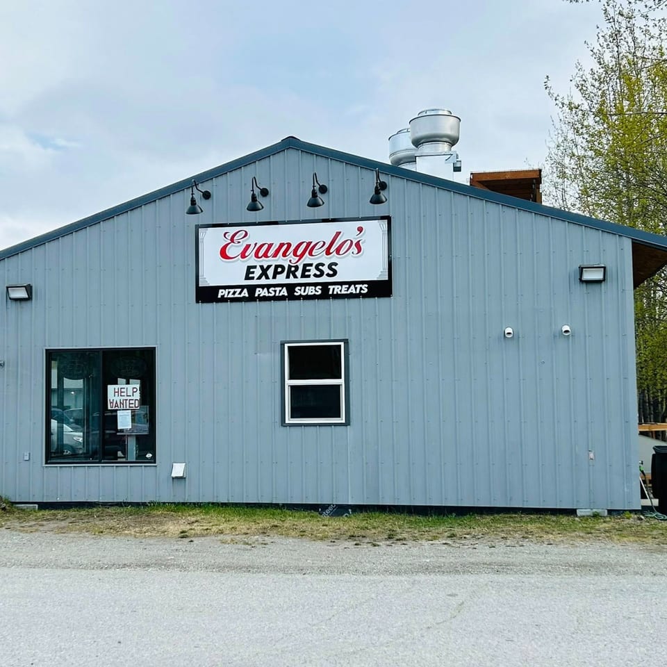 The exterior of Evangelo's Express, a gray building with a sign for pizza, pasta, subs, and treats.