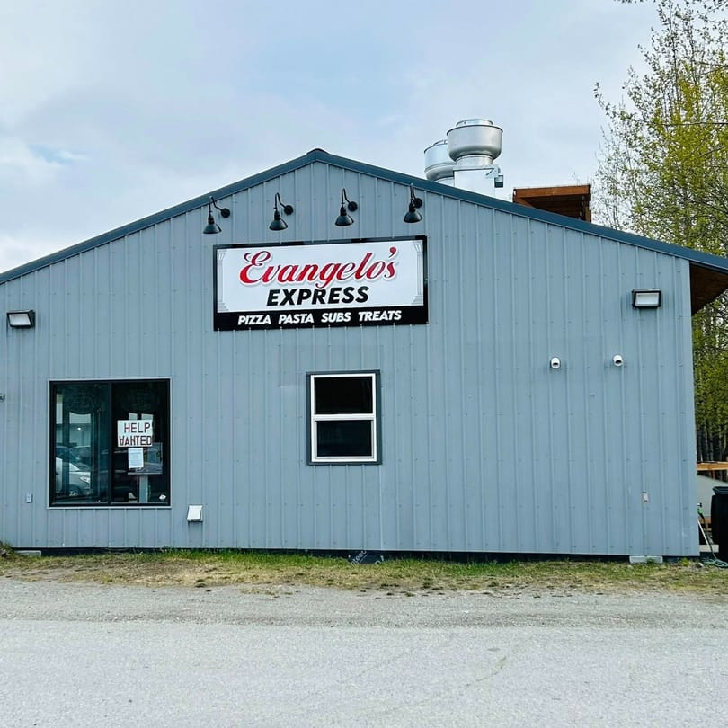 The exterior of Evangelo's Express, a gray building with a sign for pizza, pasta, subs, and treats.